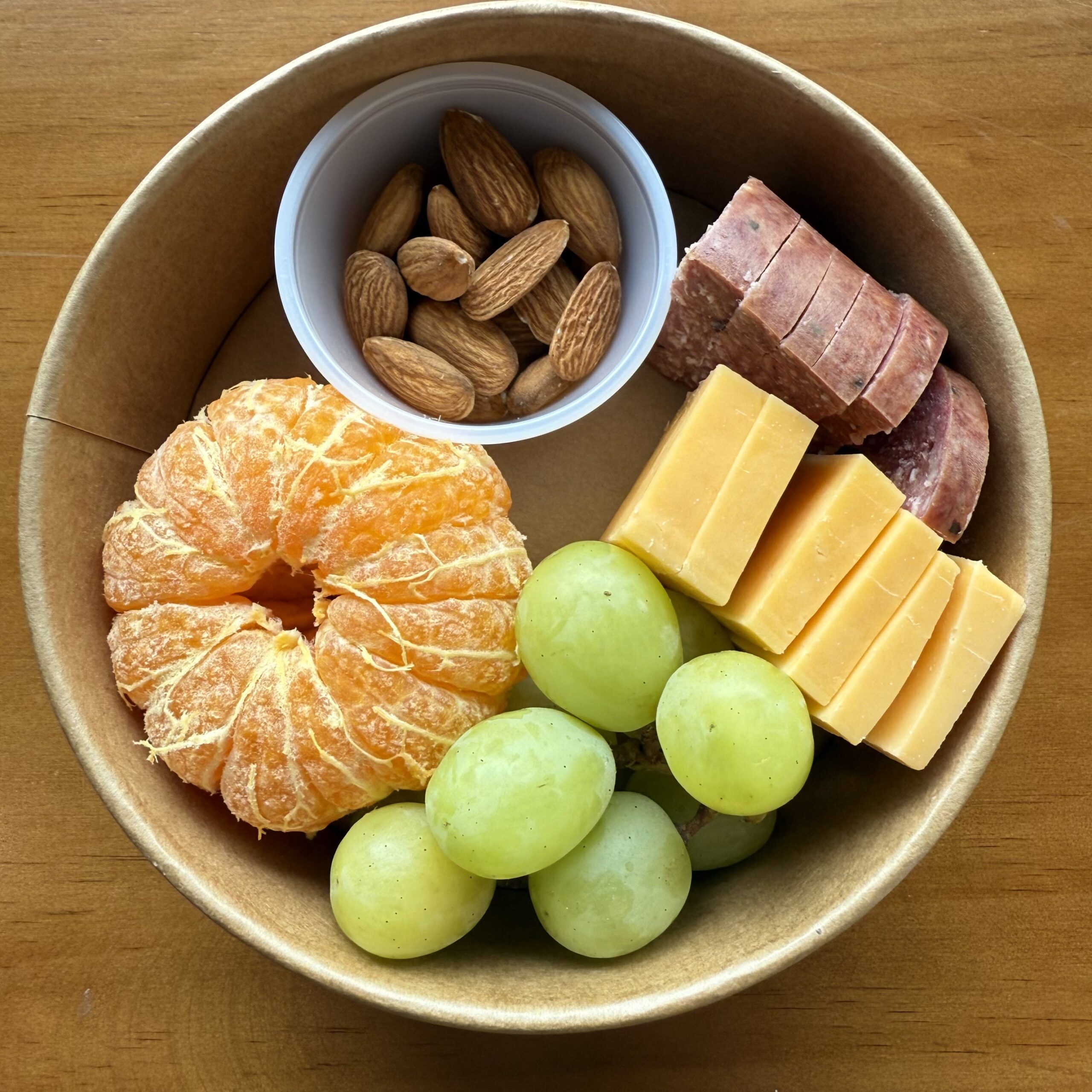 snack bowl with orange, grapes, cheese, sausage and almonds